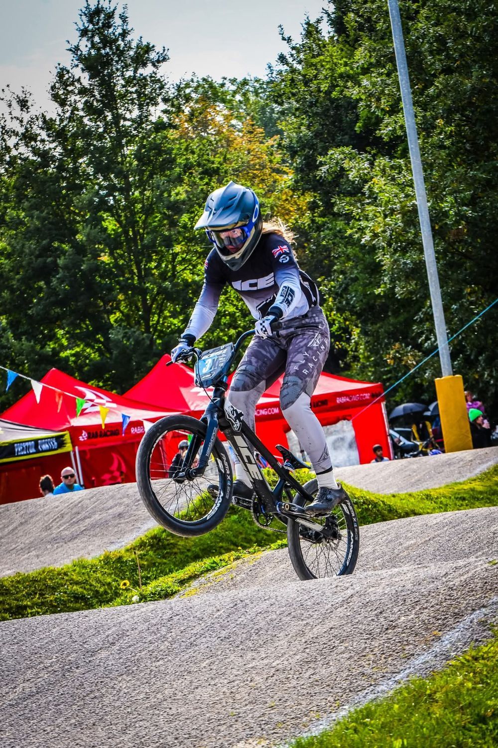 BMX rider in race kit riding over a jump on the track